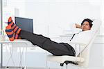 Businessman relaxing in his swivel chair with feet up in his office