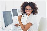 Pretty casual businesswoman smiling at camera at desk in her office