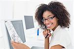 Pretty photo editor smiling at camera at desk in her office