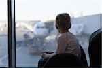 cute boy waiting at the airport and enjoying plane view