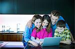 Family using laptop in kitchen