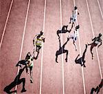 Relay runners handing off baton on track