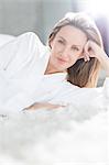 Woman in bathrobe laying on bed