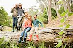 Students and teacher sitting on log in forest