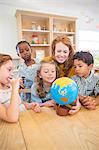 Students and teacher examining globe in classroom