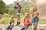 Students and teacher using binoculars in forest