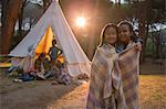 Girls wrapped in blanket at campsite