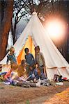 Students and teacher reading at teepee at campsite