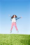 Girl jumping for joy on grassy hill