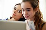 Mother watching daughter use laptop