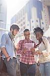 Friends using digital tablet on city street