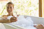 Woman having champagne in bubble bath