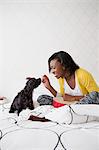 A young girl and her small black dog on a bed.