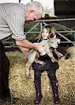 A girl holding a small new-born lamb.