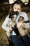 A girl holding two small lambs.