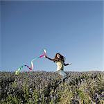 A child, a girl running with a paper streamer fluttering in the wind.