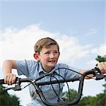 A young boy leaning over the handlebars of a bicycle.