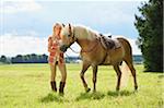 Portrait of a young woman standing beside her Haflinger horse in a field in summer, Upper Palatinate, Bavaria, Germany