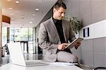 Mid adult businessman on office desk using digital tablet