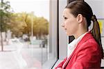 Portrait of unhappy young businesswoman gazing through window