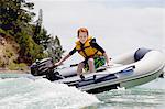 Boy steering speeding motor dinghy at sea