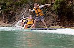 Brothers and sister splashing from paddleboard at sea