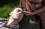 Overhead close up view of anxious male soldier with wife soothing his forehead in garden