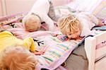 Three young brothers crawling face down on bed