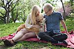Young couple with corgi dog sitting in park
