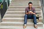 Young man texting on smartphone on city stairway