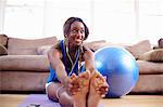 Young woman exercising and touching toes on sitting room floor