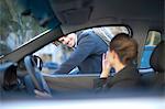 Young businesswoman driving and waving at male cyclist