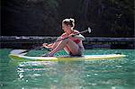 Mid adult woman sit down paddleboarding at sea