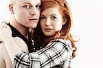 Studio portrait of red haired young couple hugging cheek to cheek