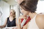 Four businesswomen looking at blueprint designs in office