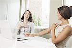 Two businesswoman laughing in office