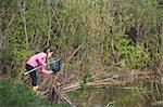 Girl retrieving frog from fishing net at pond