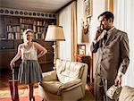 Young vintage couple in sitting room with vintage telephone and vacuum cleaner