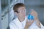 Male scientist holding up erlenmeyer flask in lab