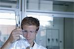 Young male scientist analyzing volumetric flask in lab