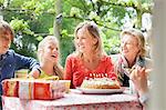 Girl making birthday wish with her family at birthday party