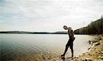 Young male hiker taking apprehensive paddle in lake