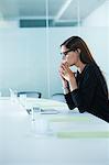 Worried female office worker using laptop at conference table