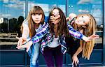 Three young women in a row leaning forward and covering mouth