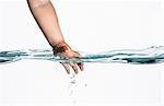 Surface level view of toddlers hand reaching into clear water