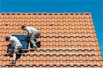 Workers installing solar panel on roof framework of new home, Netherlands