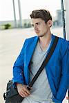 Serious young man leaning against wall