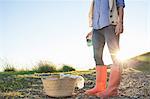 Young woman in wellies standing against sunset