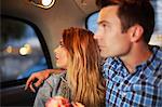 Couple looking out of city taxi window at night