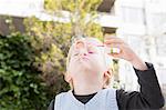 Young boy blowing bubbles in garden